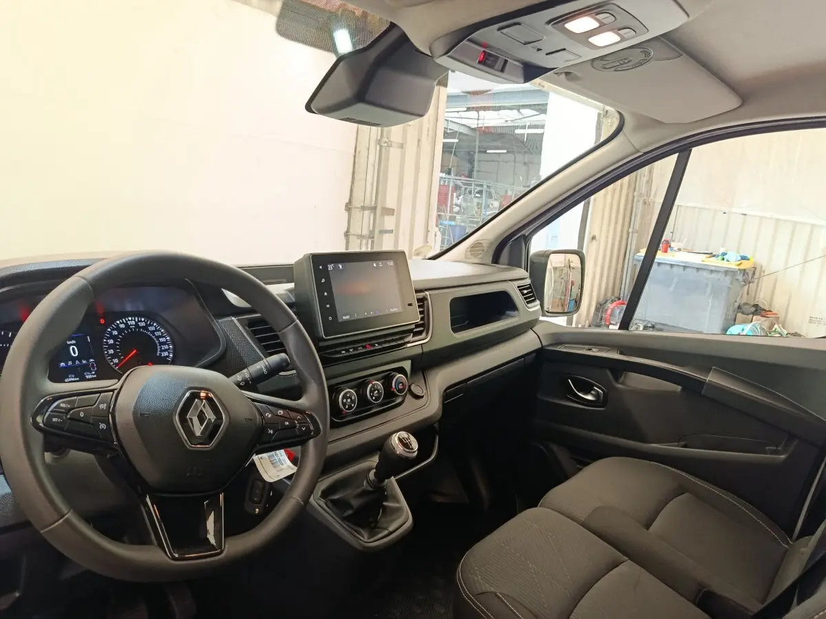 Vue intérieure côté conducteur du Renault Trafic Fourgon 2023, volant multifonctions et tableau de bord moderne.
