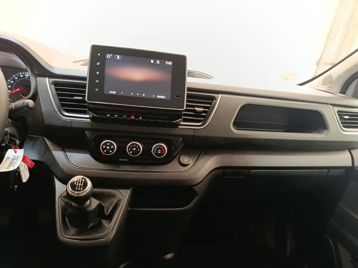 Vue intérieure du tableau de bord du Renault Trafic Fourgon 2023, avec écran tactile et levier de vitesses manuel.