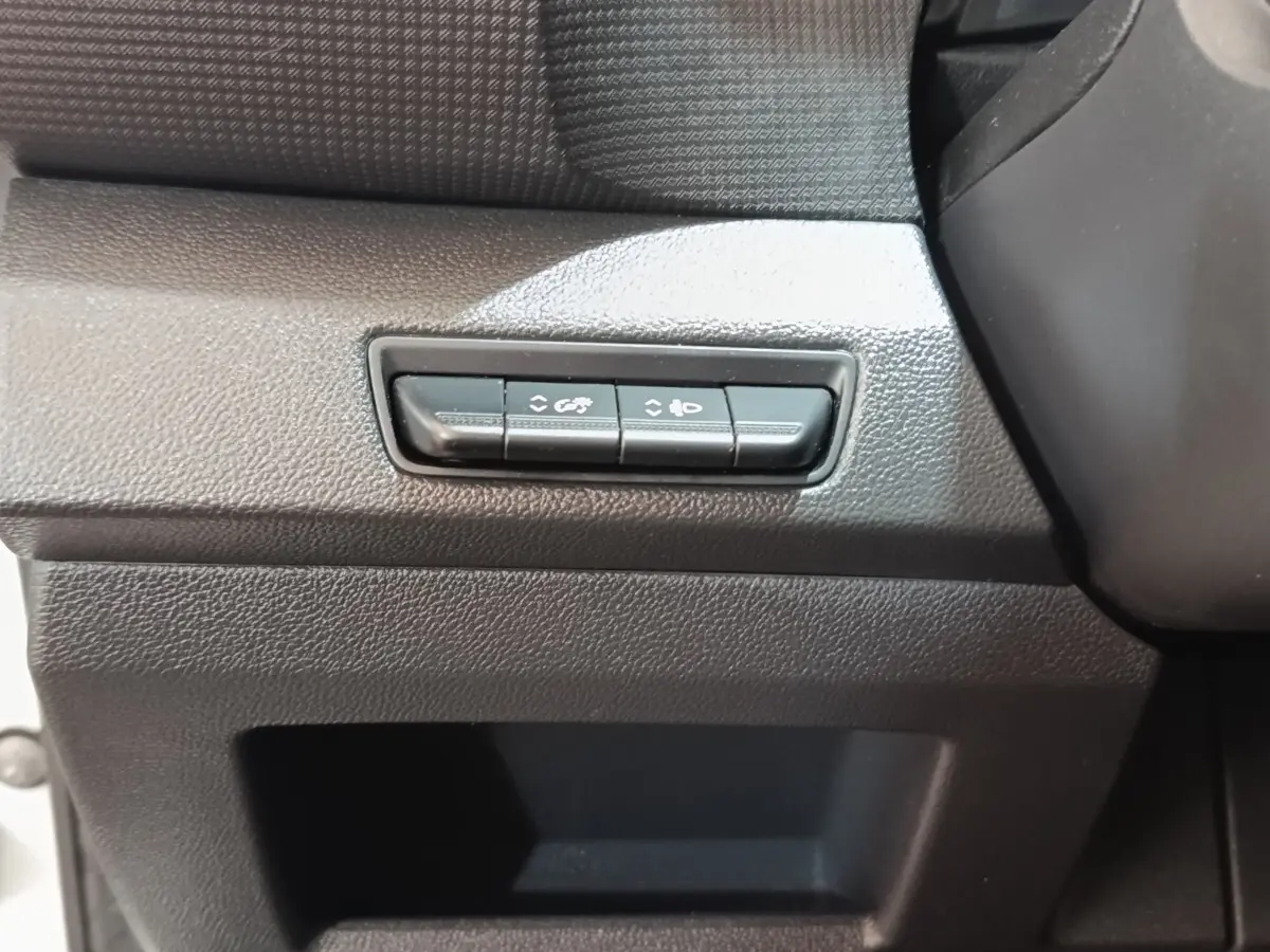 Gros plan sur les boutons de réglage des phares et de l’éclairage intérieur du tableau de bord noir du Renault Trafic Fourgon blanc.