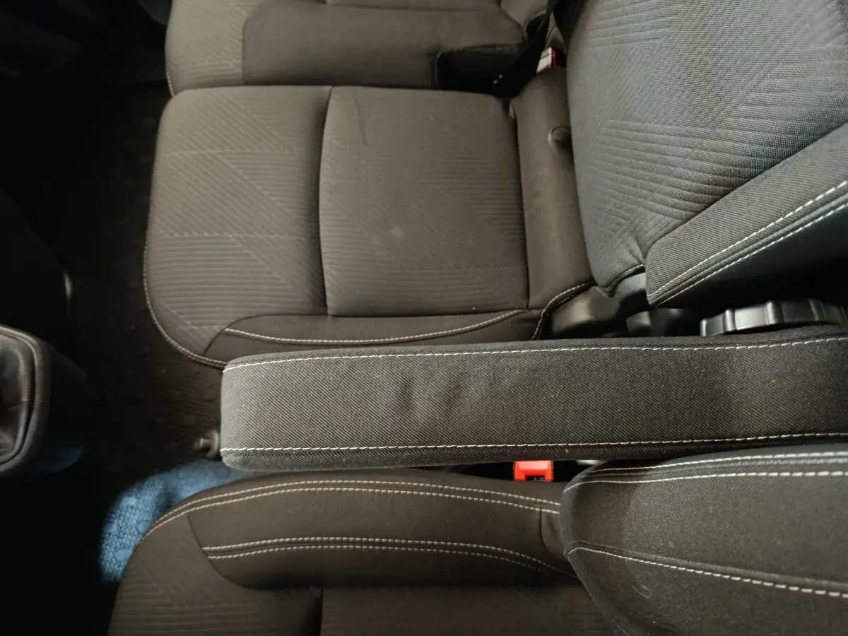 Vue plongeante sur les sièges avant noirs avec accoudoir central du Renault Trafic Fourgon blanc 2023.