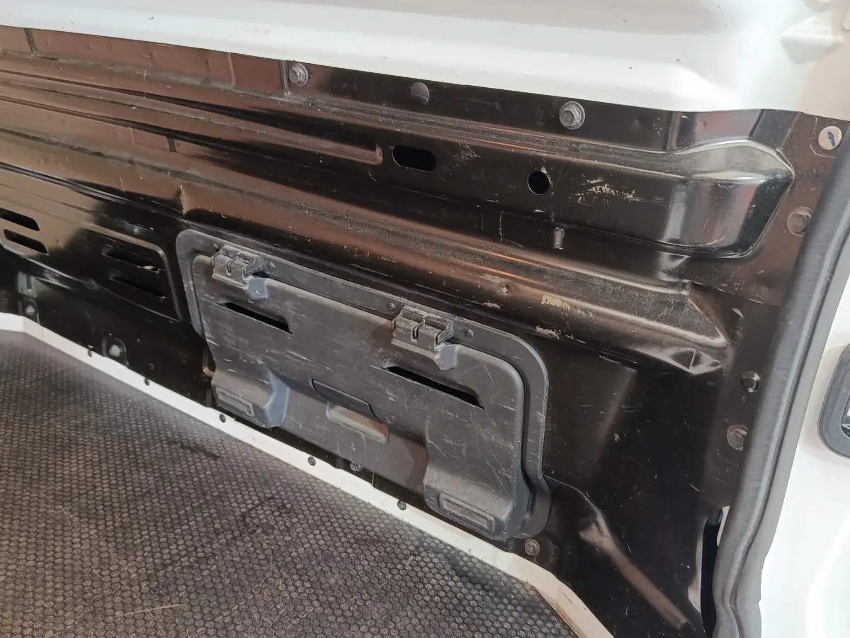 Détail intérieur de la cloison pleine noire du Renault Trafic Fourgon blanc, vue rapprochée côté chargement.