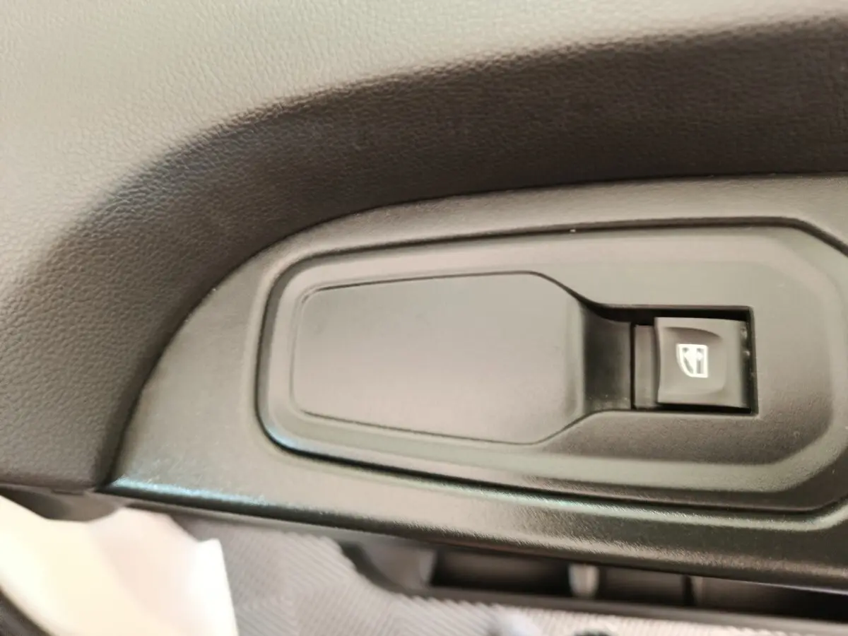 Bouton de commande de lève-vitre électrique sur la porte intérieure d’un Renault Trafic Fourgon blanc.