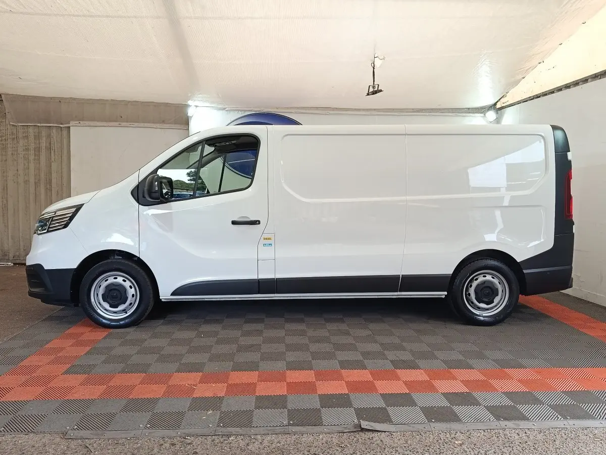 Vue de profil côté gauche d’un Renault Trafic Fourgon blanc 2023 avec jantes acier et portes latérales pleines.