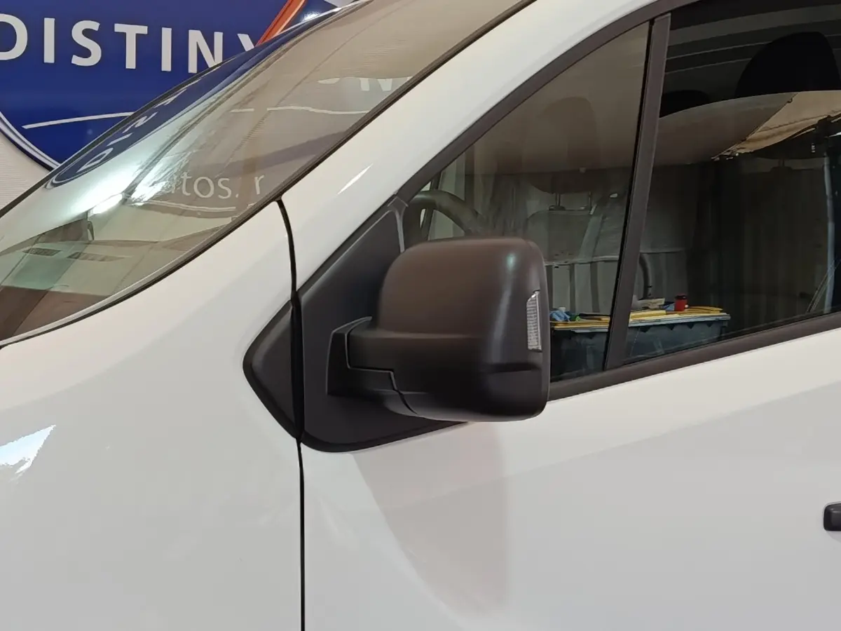 Gros plan sur le rétroviseur noir côté conducteur du Renault Trafic Fourgon blanc, vue latérale avant droite.