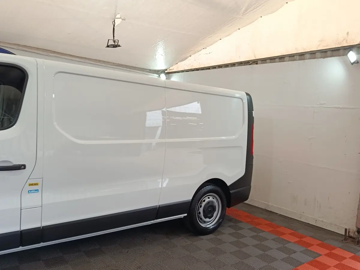 Vue latérale droite d’un Renault Trafic Fourgon blanc 2023 avec jante acier et bandeau noir inférieur.