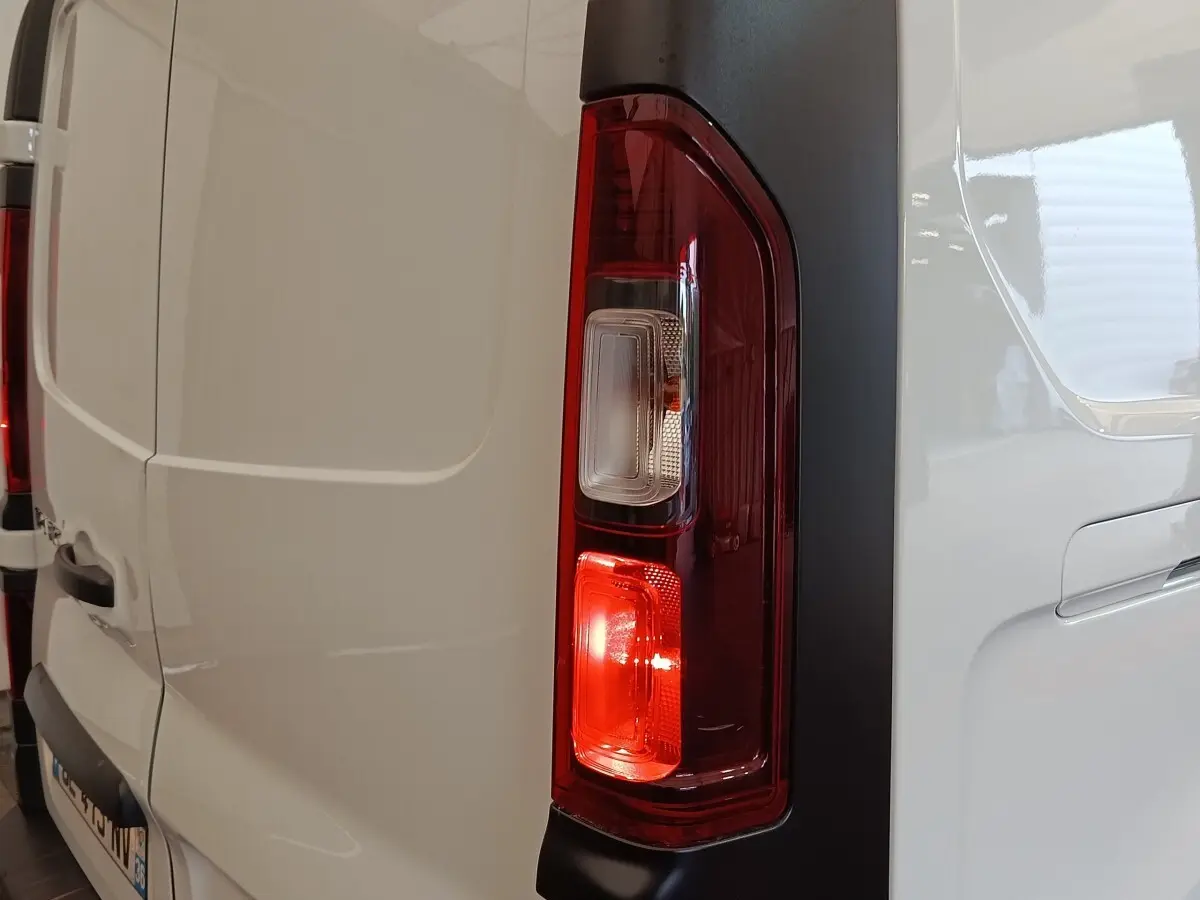 Gros plan sur le feu arrière droit rouge et blanc du Renault Trafic Fourgon blanc, vue arrière côté droit.