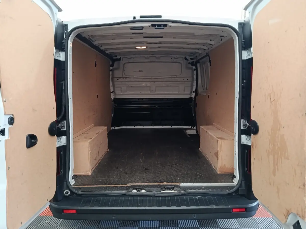 Vue arrière du Renault Trafic Fourgon blanc 2023, montrant l'espace de chargement vide avec cloison pleine en bois.