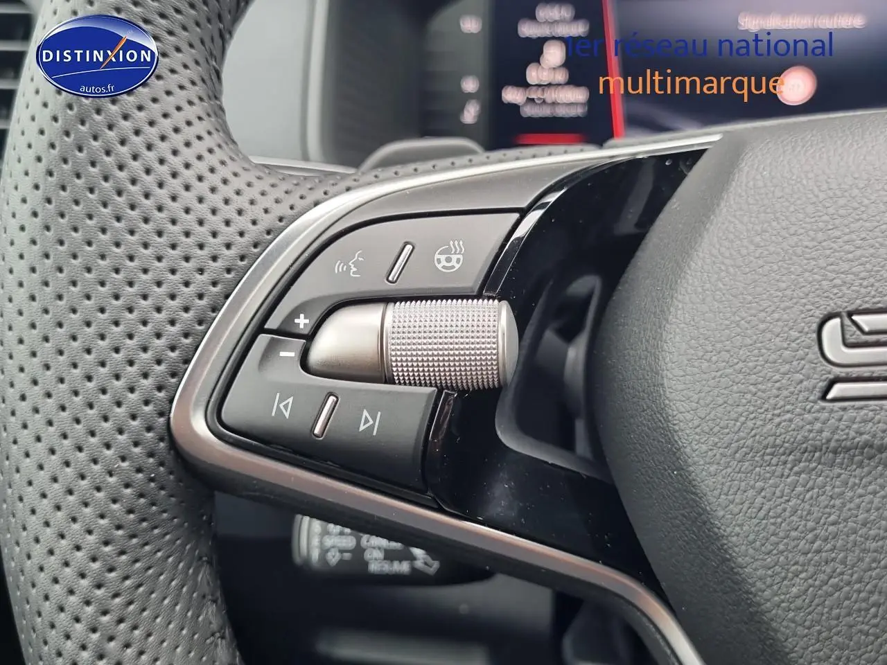 Gros plan sur les commandes au volant cuir perforé du Skoda Karoq noir, version sportline 2025.