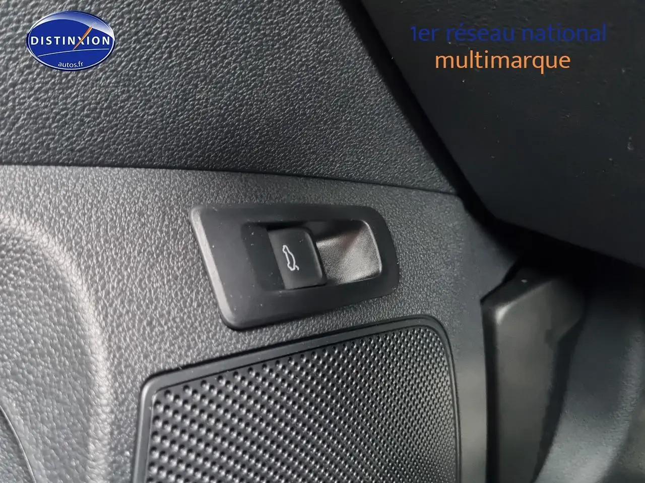 Gros plan sur le bouton d'ouverture du coffre et la grille du haut-parleur dans l'habitacle noir du Skoda Karoq 2025.