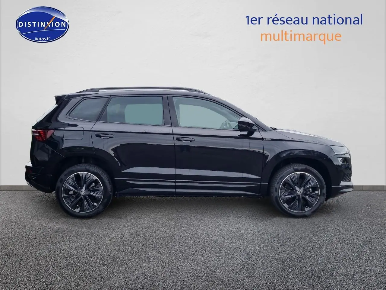 Vue de profil côté gauche d'un Skoda Karoq noir 2025 avec jantes alu et barres de toit.