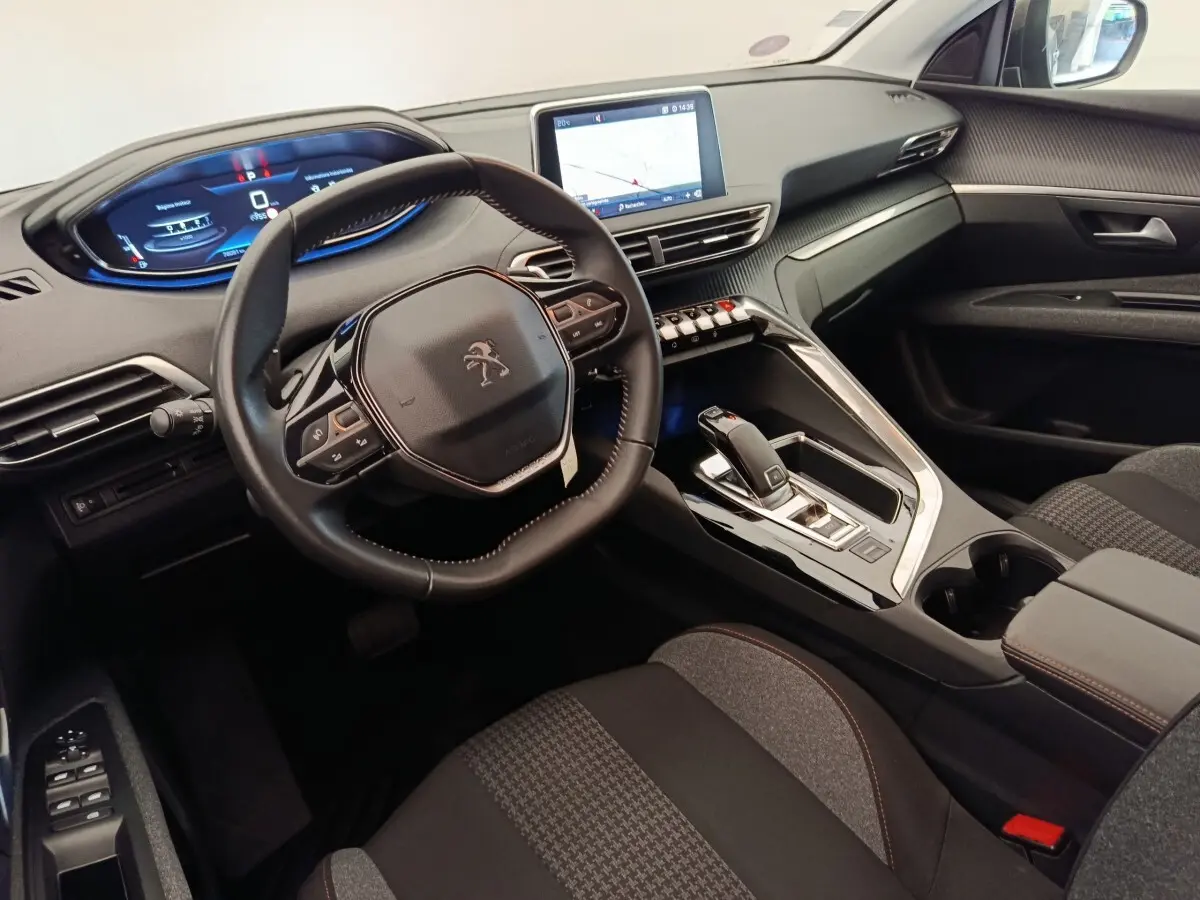 Intérieur Peugeot 5008 vu côté conducteur, tableau de bord moderne avec écran tactile et volant cuir noir.