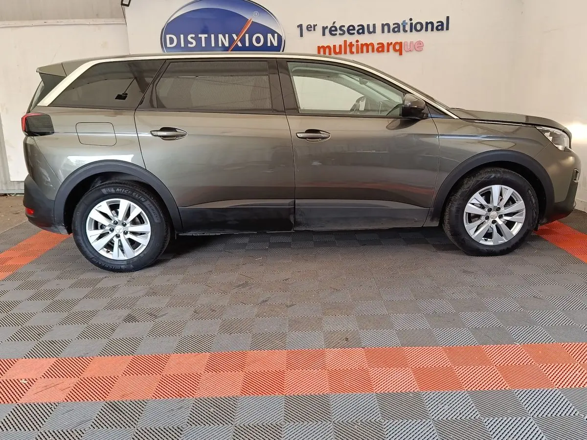Profil droit d'un Peugeot 5008 gris foncé 2020 avec jantes alliage et vitres teintées, stationné en intérieur.