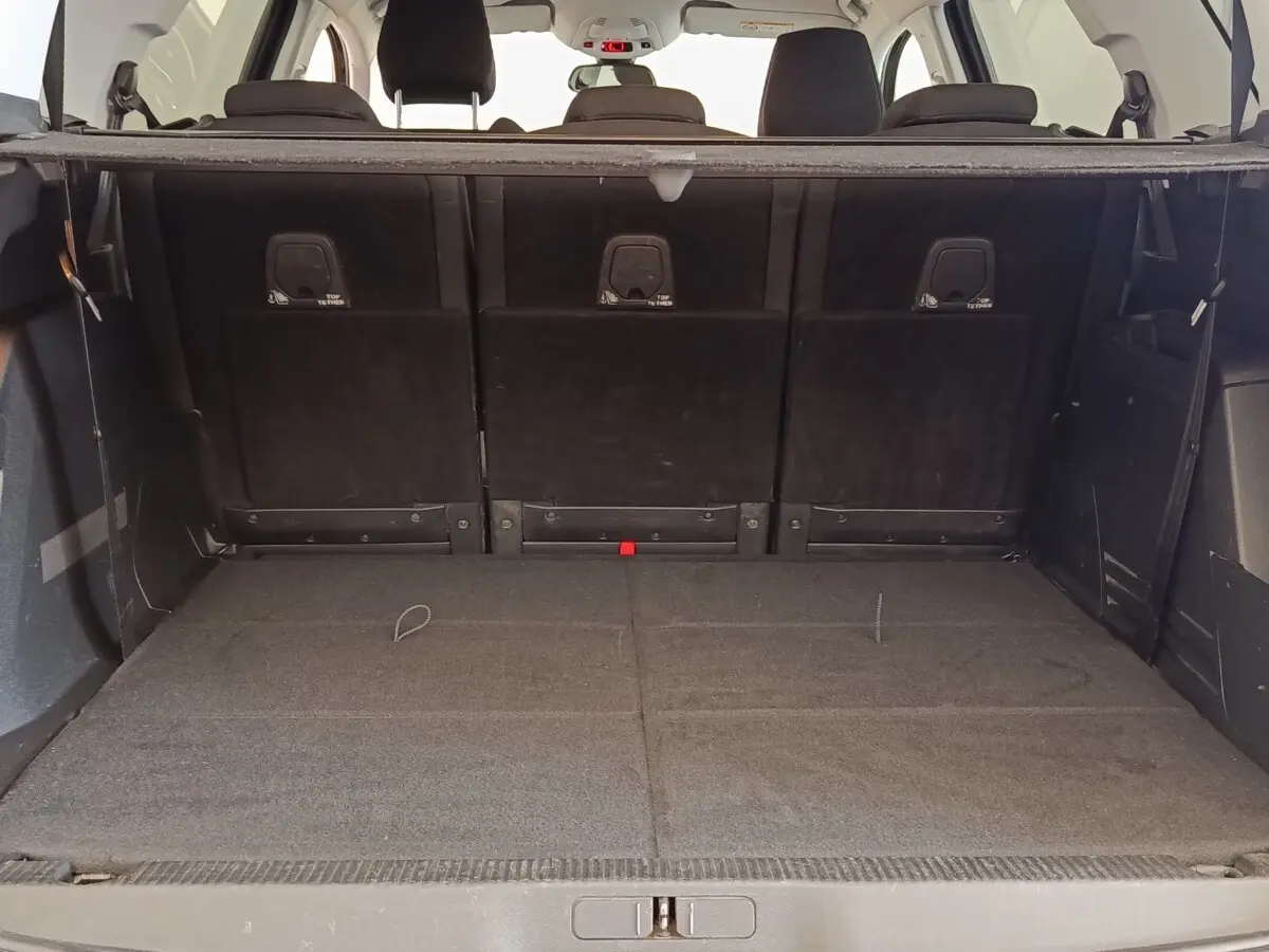 Vue intérieure du coffre spacieux du Peugeot 5008 gris foncé, avec sièges arrière rabattus et tablette de séparation visible.