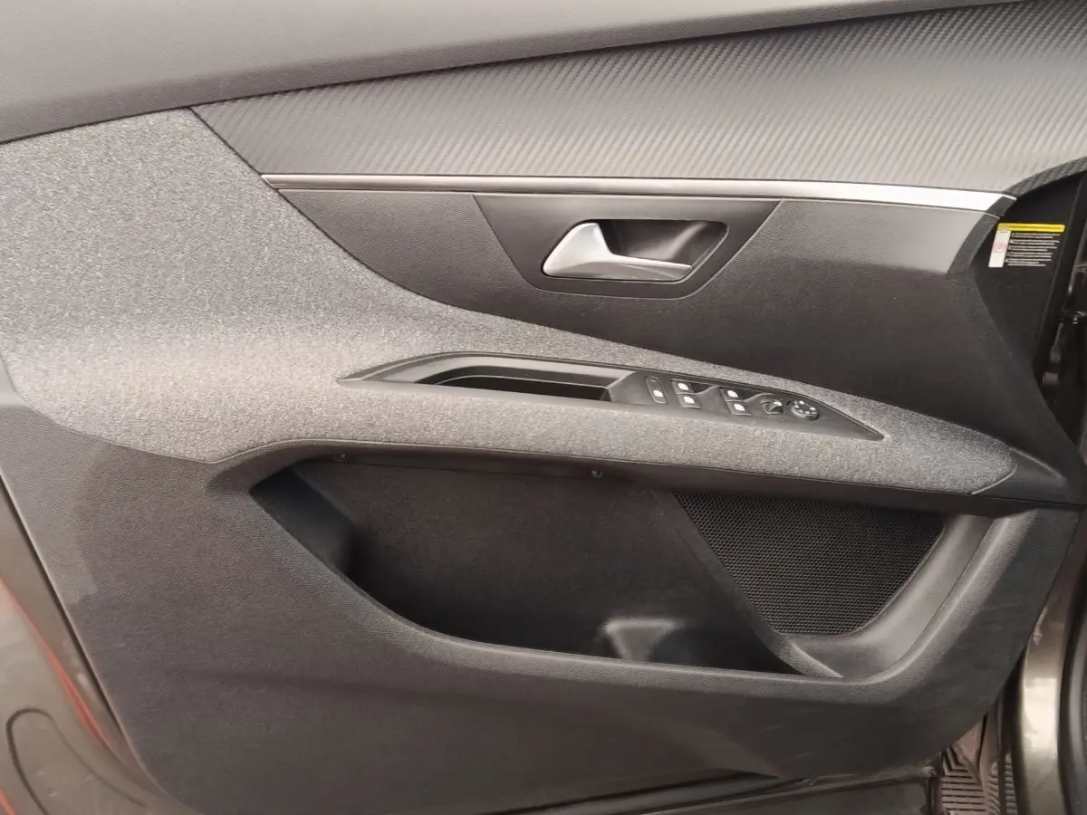Gros plan sur la porte avant droite grise du Peugeot 5008 2020, avec commandes électriques et habillage tissu.