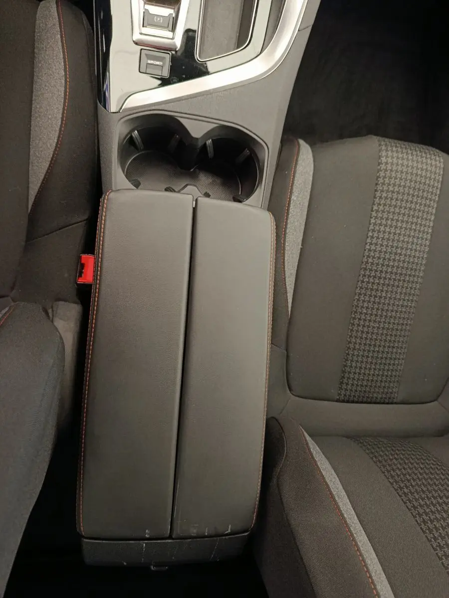 Vue plongeante sur la console centrale et les sièges avant en tissu noir avec surpiqûres rouges du Peugeot 5008 gris foncé.