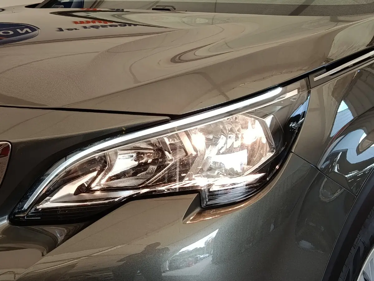 Gros plan sur le phare avant droit du Peugeot 5008 gris foncé, mettant en valeur son design moderne et lumineux.