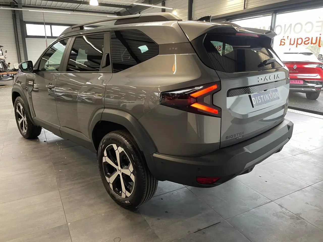 Vue 3/4 arrière droite du Dacia Bigster gris schiste avec feux arrière LED en forme de flèche et jantes alliage diamantées.