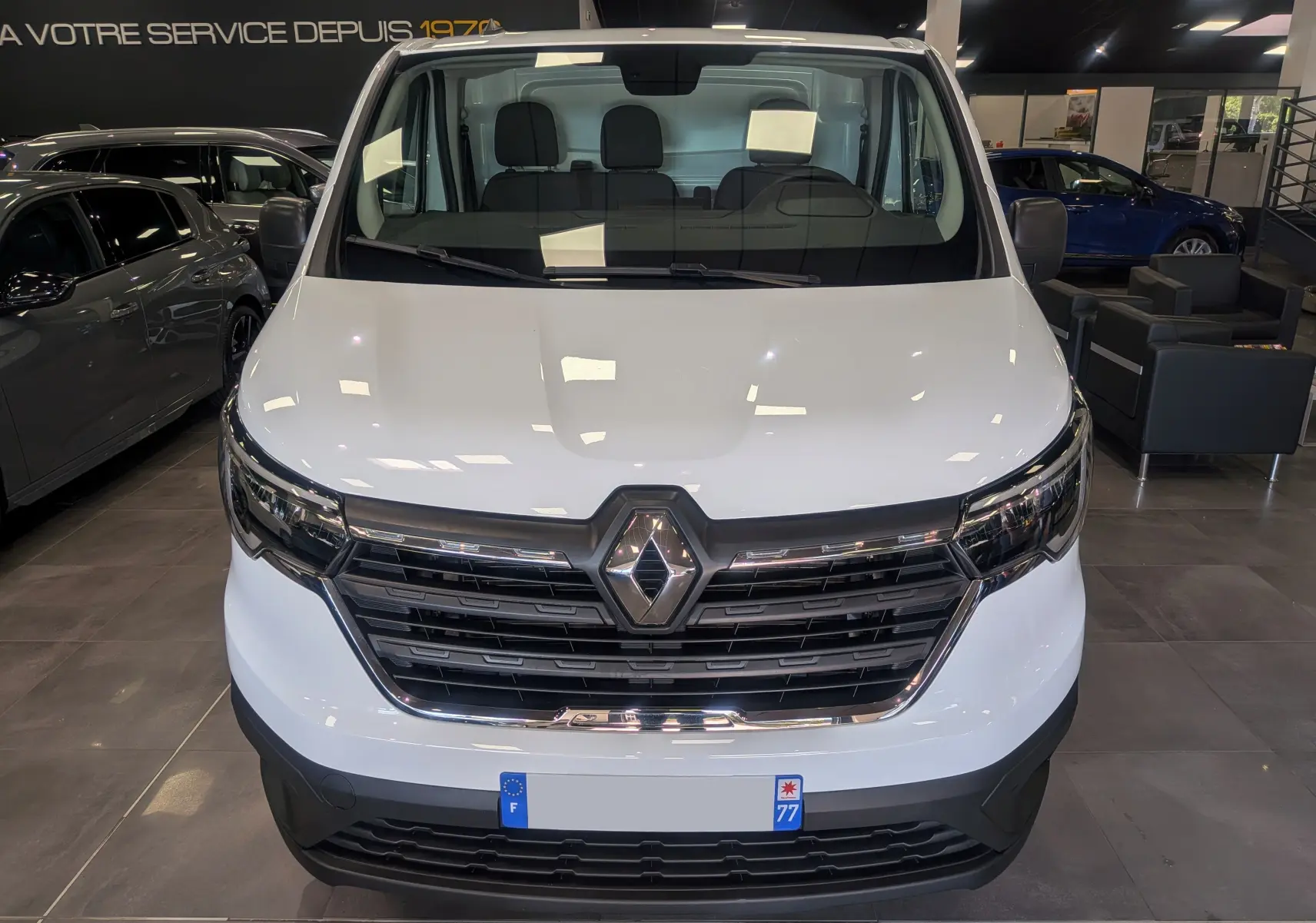 Vue frontale d’un Renault Trafic Fourgon blanc minéral 2024, avec calandre noire et logo Renault central bien visible.