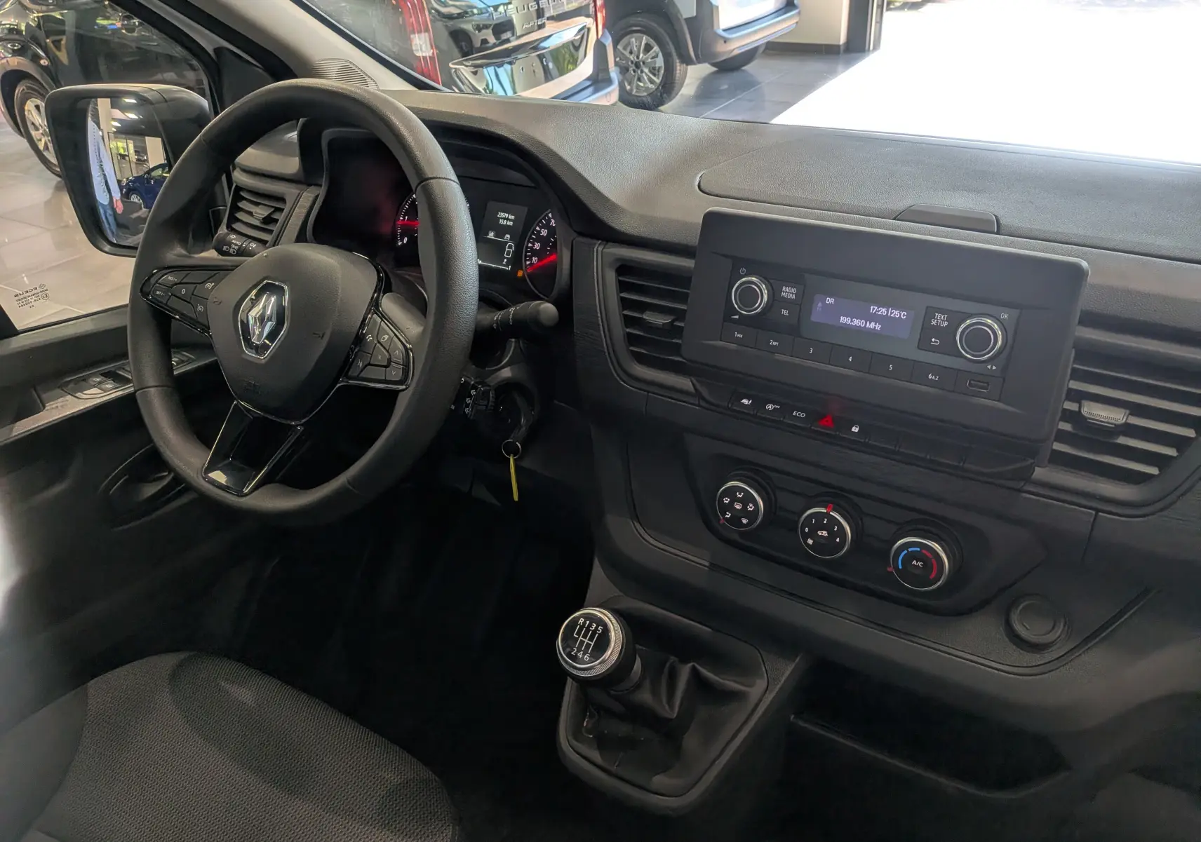 Vue intérieure côté conducteur du Renault Trafic Fourgon 2024, tableau de bord noir avec volant multifonction et levier de vitesse manuel.