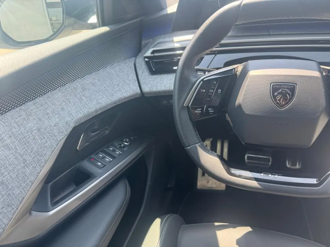Vue intérieure côté conducteur du Peugeot 3008 Hybrid 145 e-DCS6 GT 2025, volant GT et garniture tissu gris.