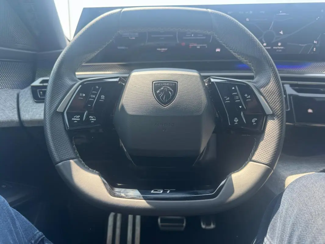 Vue rapprochée du volant noir du Peugeot 3008 Hybrid 145 e-DCS6 GT avec commandes intégrées et logo central GT.