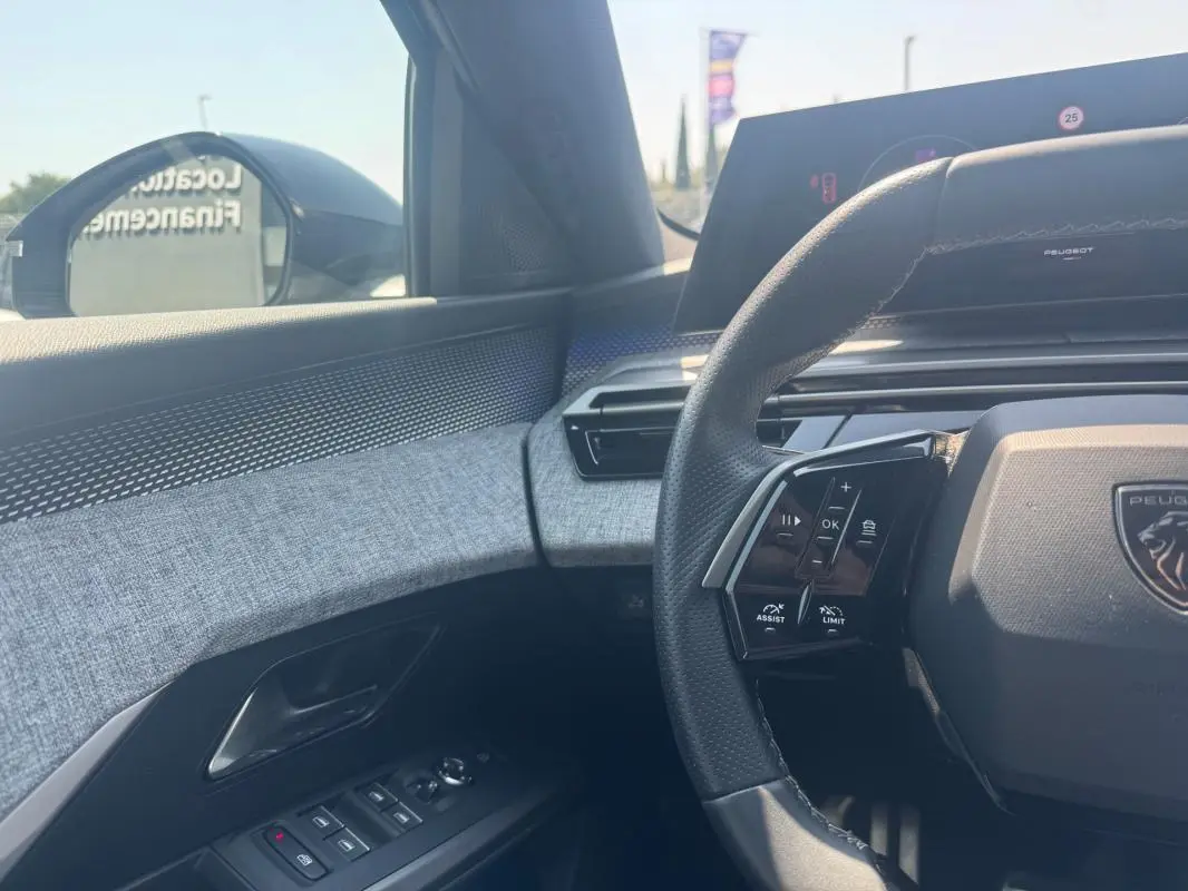 Intérieur côté conducteur du Peugeot 3008 Hybrid 145 e-DCS6 GT 2025, volant multifonction et habillage tissu gris.