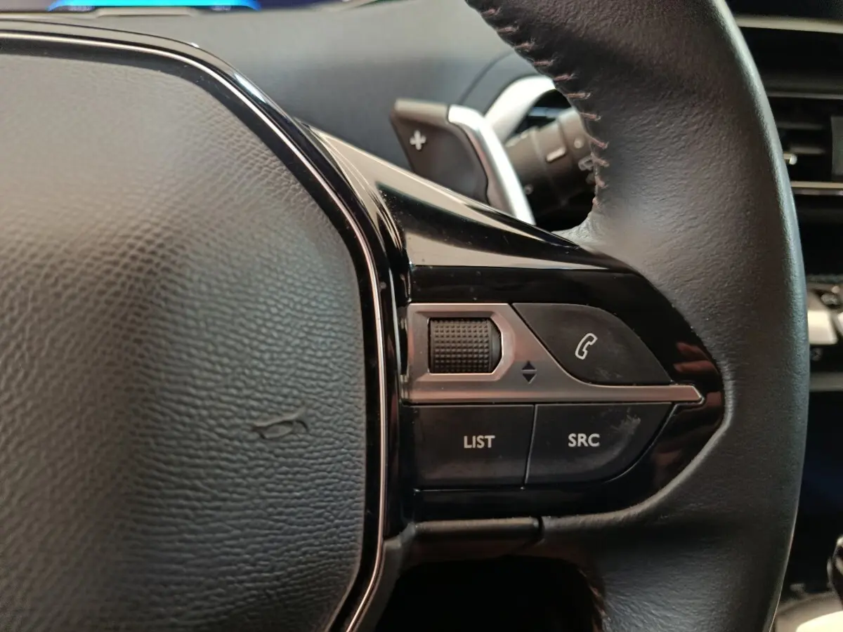 Gros plan sur la partie droite du volant cuir noir du Peugeot 3008 2022 avec commandes audio et téléphone intégrées.