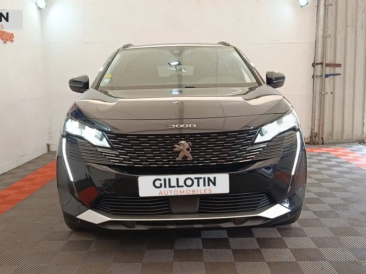 Vue frontale d'un Peugeot 3008 noir 2022 avec feux LED allumés et calandre distinctive en intérieur showroom.