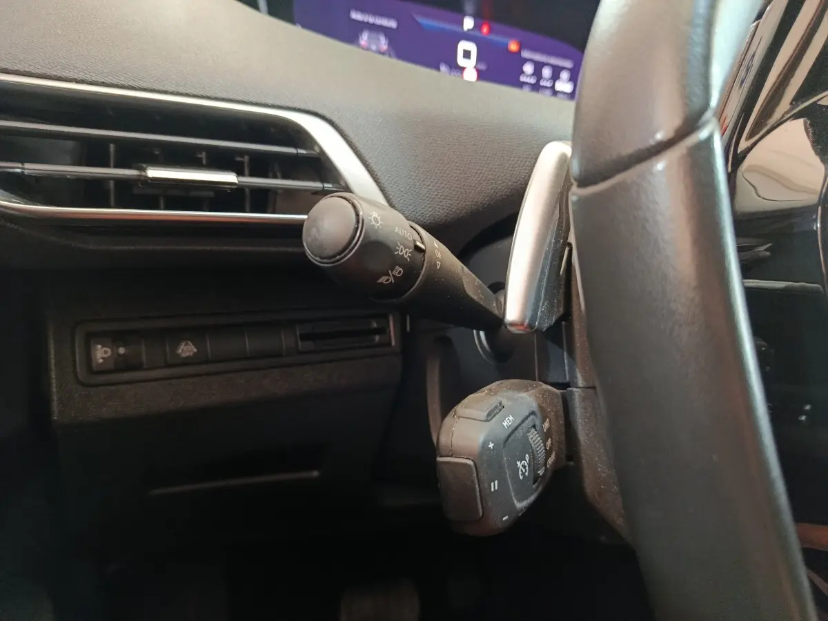 Détail côté gauche du volant noir du Peugeot 3008 2022, avec commandes d’éclairage et affichage digital partiel.