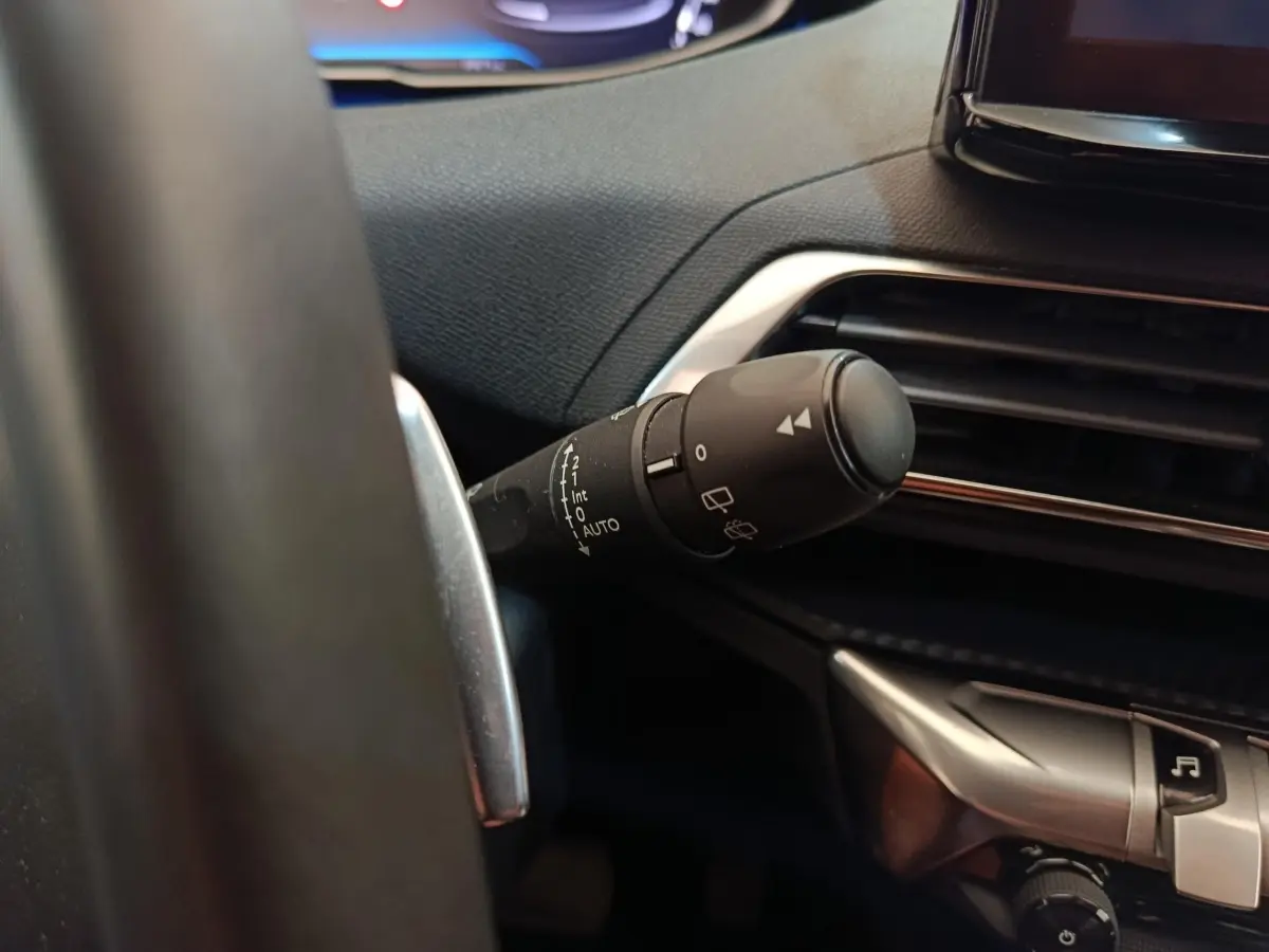Gros plan sur la commande des essuie-glaces à gauche du volant dans l’habitacle noir du Peugeot 3008 2022.
