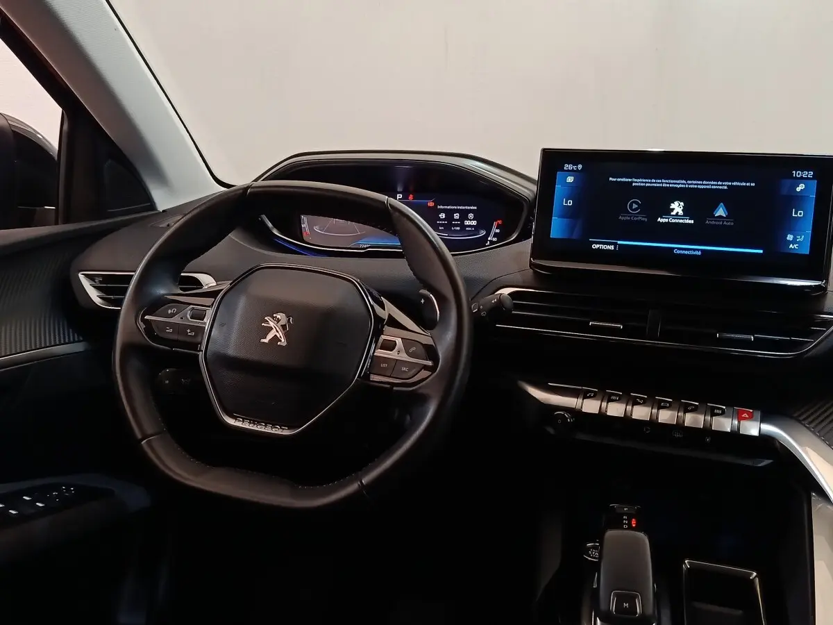 Vue intérieure avant du Peugeot 3008 noir 2022, volant cuir, tableau de bord digital et écran tactile central lumineux.