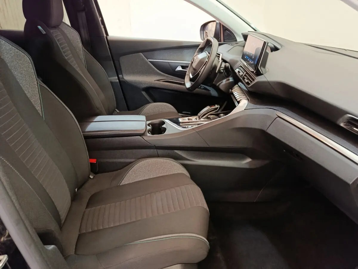 Intérieur du Peugeot 3008 2022, vue côté conducteur, sièges tissu noirs et tableau de bord avec écran tactile central.