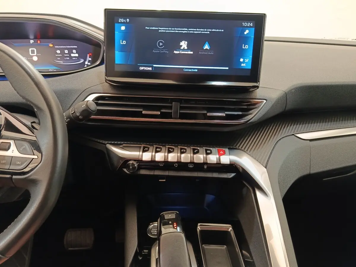 Vue intérieure centrée sur la console et l’écran tactile du Peugeot 3008 noir, avec commandes piano et volant partiel visible à gauche.