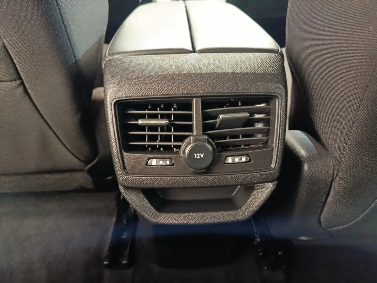 Vue rapprochée des commandes de ventilation arrière et prise 12V sur console centrale noire du Peugeot 3008 2022.