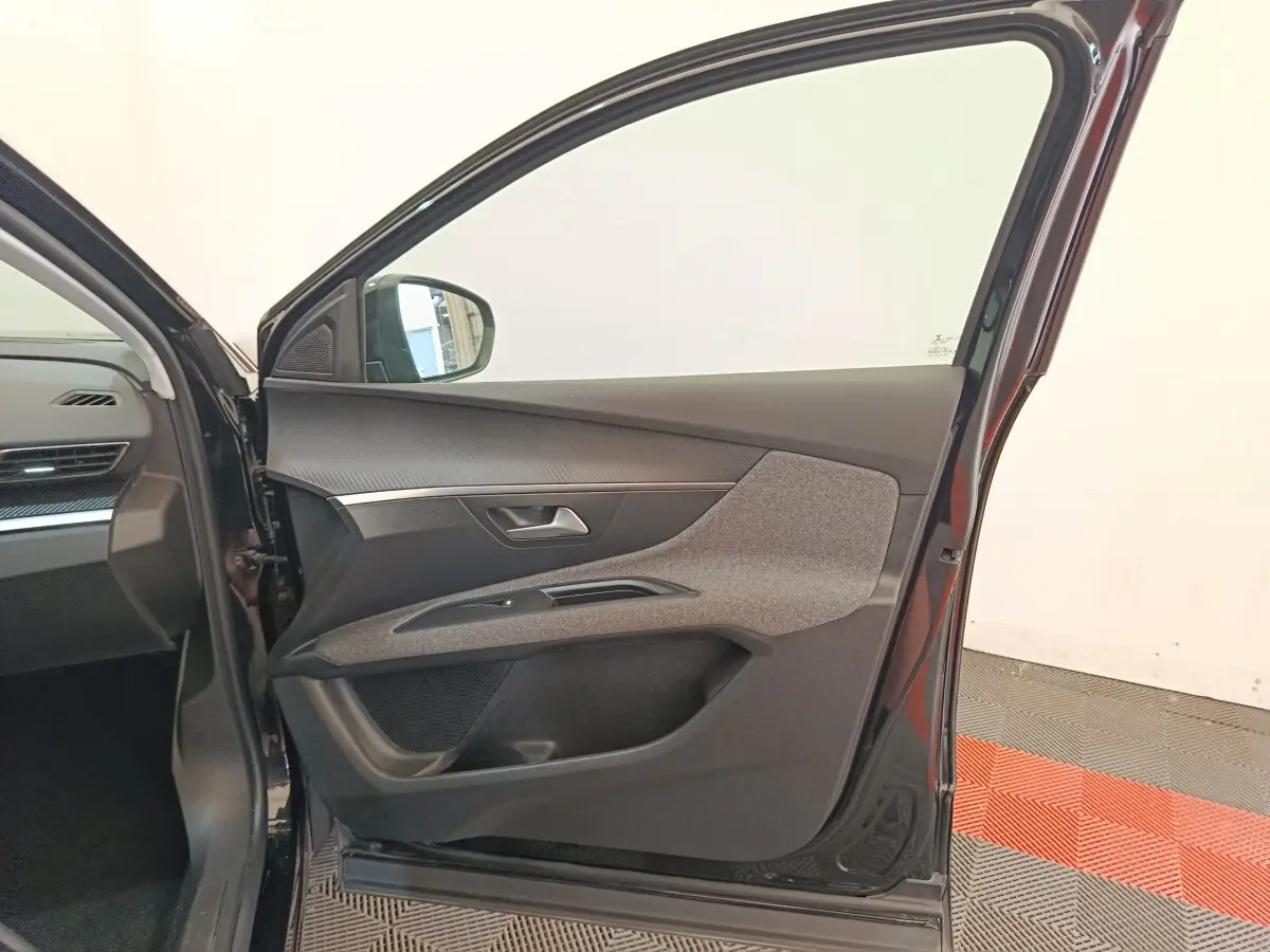 Vue intérieure côté gauche de la porte avant noire du Peugeot 3008 2022, avec garniture tissu et plastique gris.