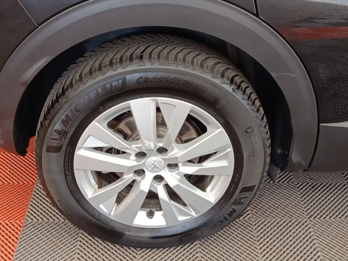 Gros plan sur la roue avant droite du Peugeot 3008 noir, mettant en valeur la jante alu et le pneu Michelin CrossClimate 2.