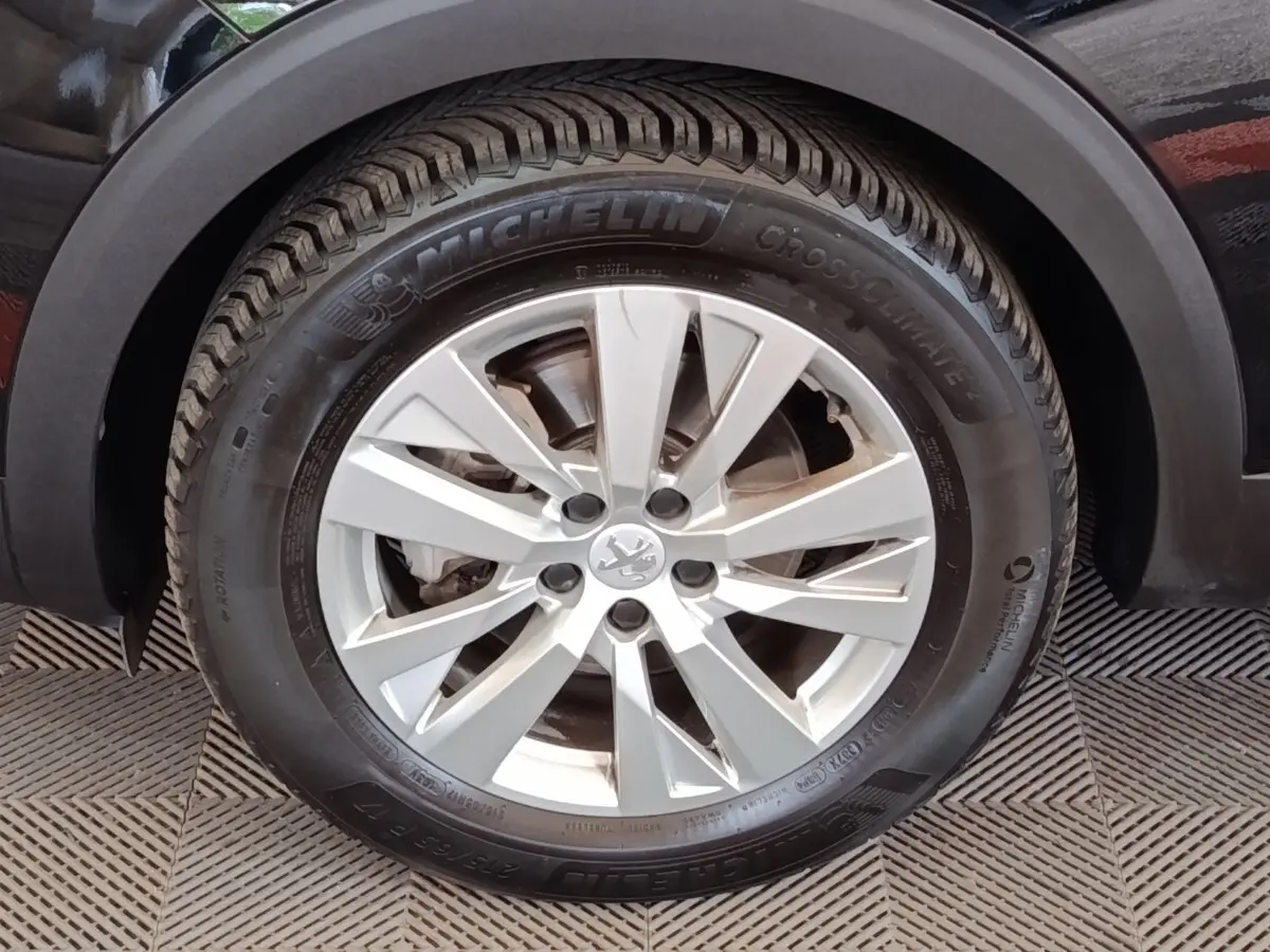 Gros plan sur la roue avant droite du Peugeot 3008 noir, jante alliage argent avec pneu Michelin CrossClimate.
