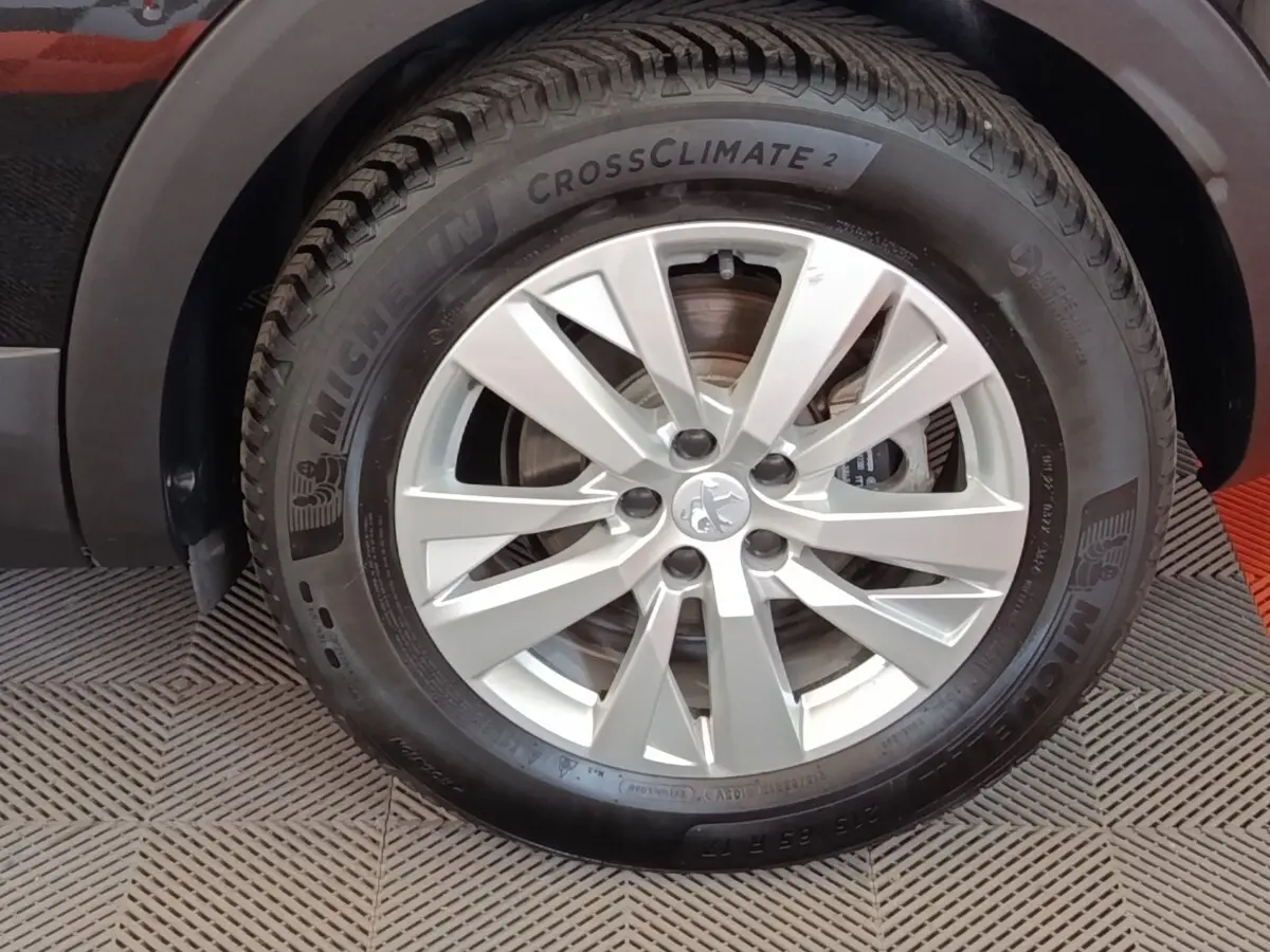 Gros plan sur la roue avant gauche d’un Peugeot 3008 noir, jante alliage argentée et pneu Michelin CrossClimate 2.