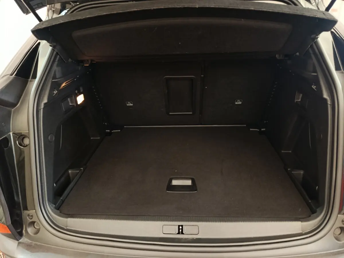 Coffre ouvert vu de l'arrière d'un Peugeot 3008 noir, espace de chargement propre et bien agencé.