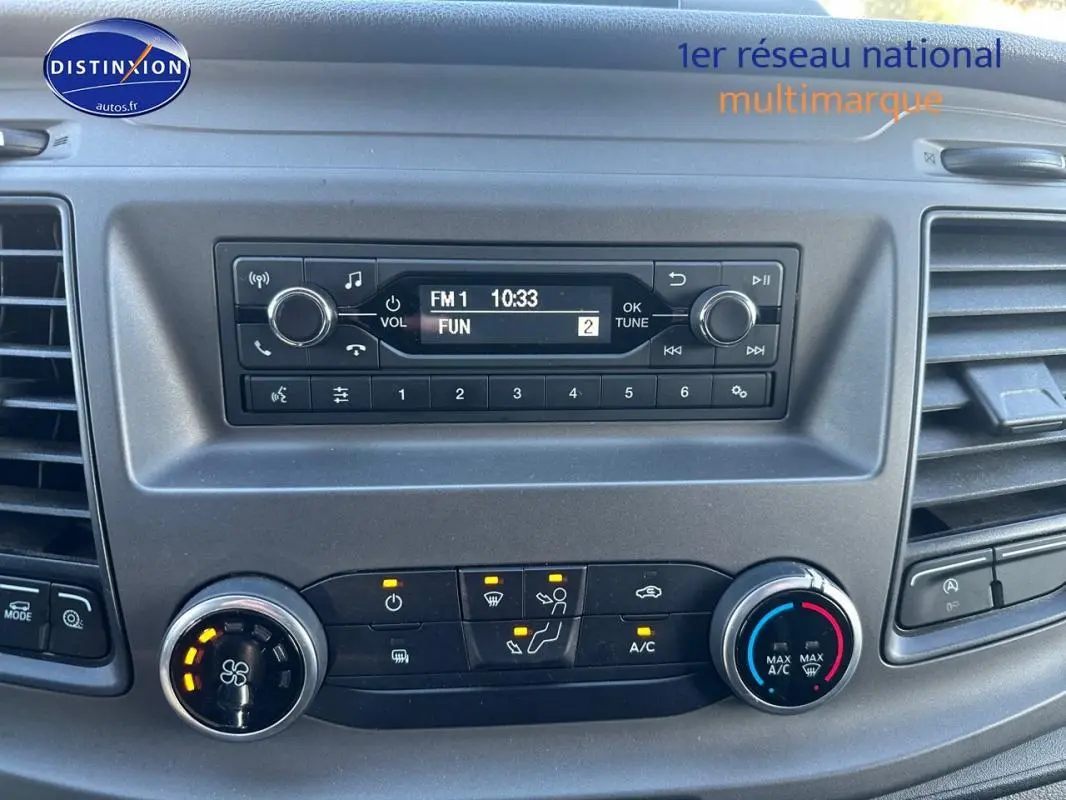 Tableau de bord du Ford Transit Custom blanc 2021, avec commandes climatisation et radio affichant FM1 à 10:33.