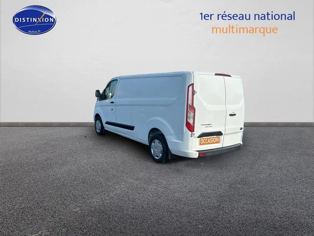 Ford Transit Custom blanc vu en 3/4 arrière droit, fourgon utilitaire avec porte latérale et vitres surteintées.