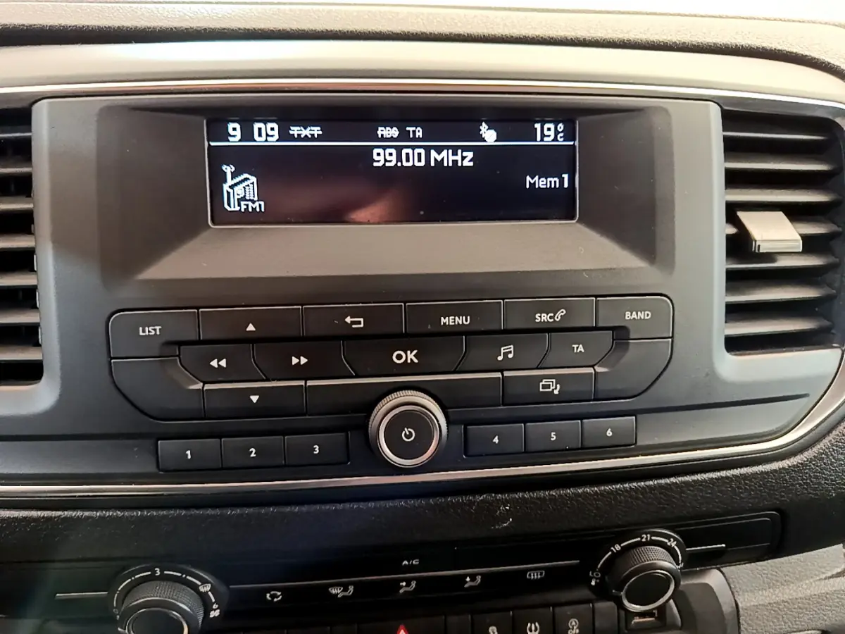 Vue rapprochée de la radio et commandes centrales du tableau de bord du Toyota Proace Verso gris clair de 2019.