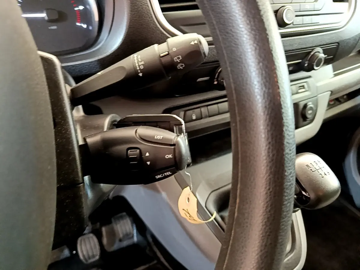 Vue rapprochée du volant et levier de vitesses manuel du Toyota Proace Verso gris clair, tableau de bord en arrière-plan.