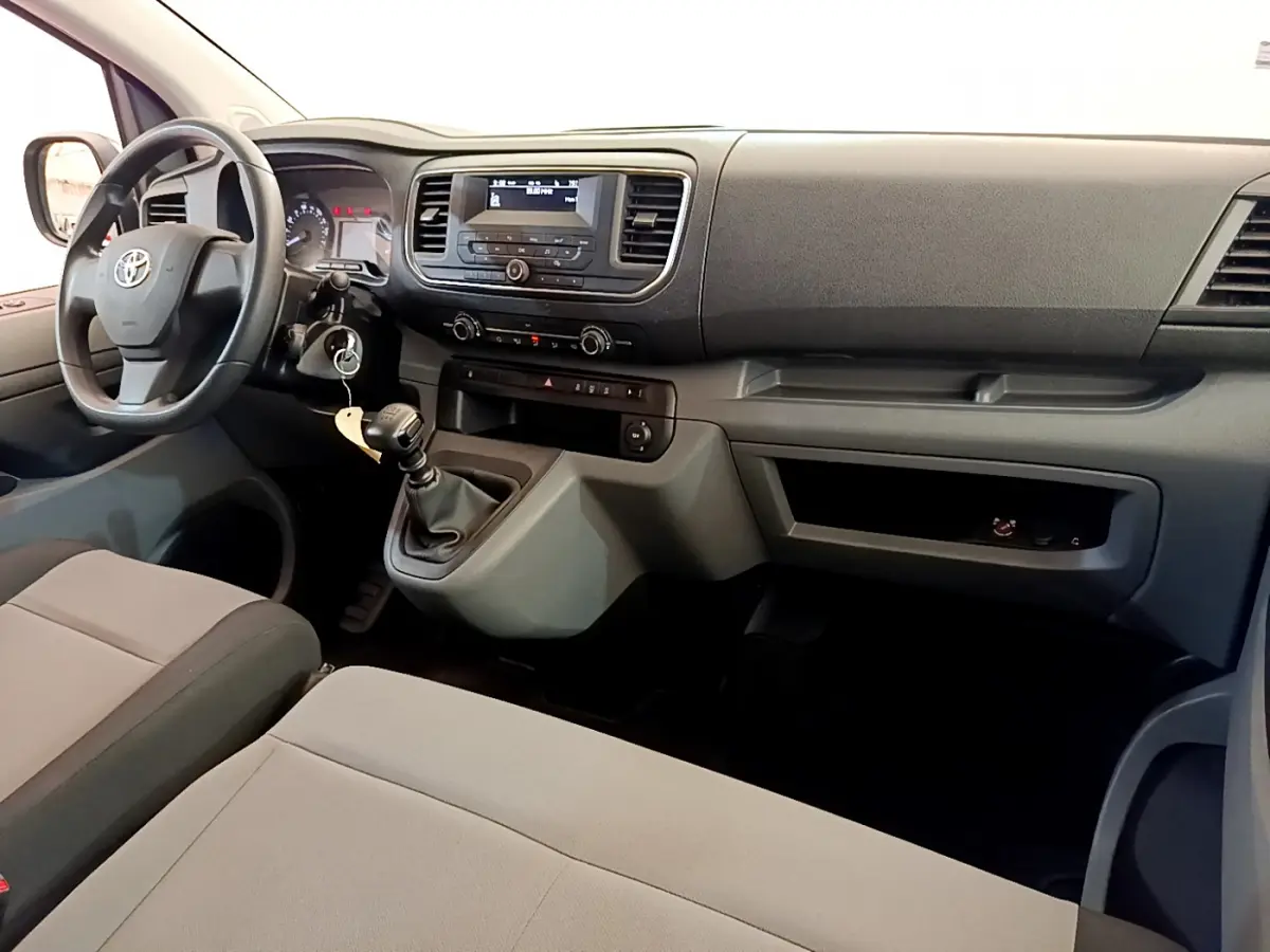 Intérieur avant du Toyota Proace Verso 2019, tableau de bord gris avec volant multifonction et levier de vitesses manuel.