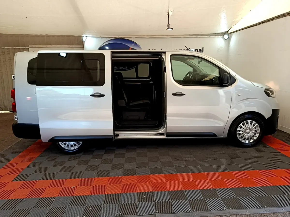 Vue latérale droite d'un Toyota Proace Verso gris clair avec porte coulissante ouverte montrant l'intérieur.