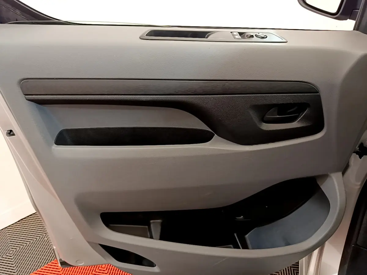 Intérieur côté gauche de la porte avant gris clair du Toyota Proace Verso 2019 avec commandes de vitres et poignée noire.