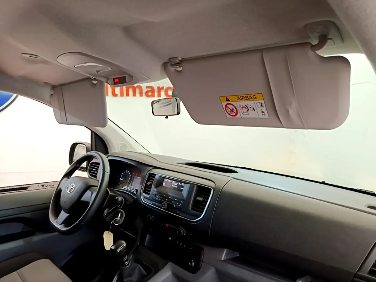 Vue intérieure côté conducteur du Toyota Proace Verso 2019, tableau de bord noir avec volant multifonctions et pare-soleil baissé.