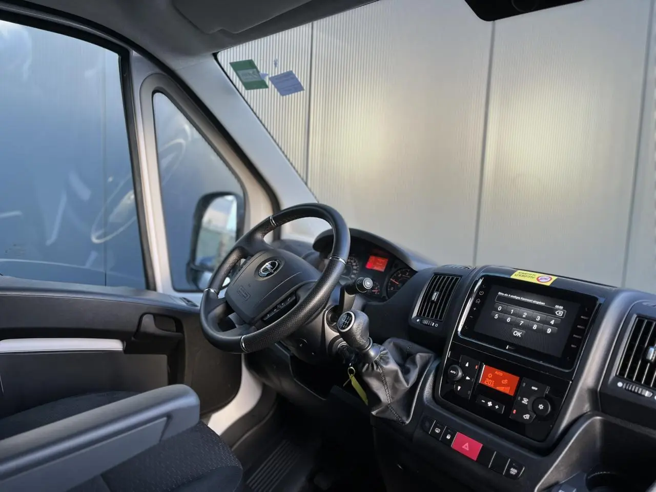 Vue intérieure côté conducteur du fourgon blanc Opel Movano 2024, montrant le volant, la boîte manuelle et l'écran tactile central.