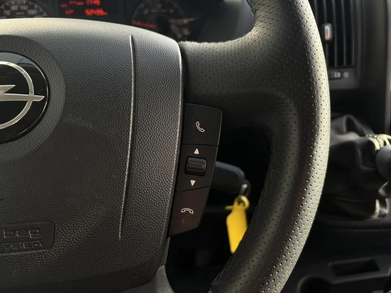 Gros plan sur le volant noir perforé de l’Opel Movano Fourgon 2024 avec commandes téléphoniques intégrées.