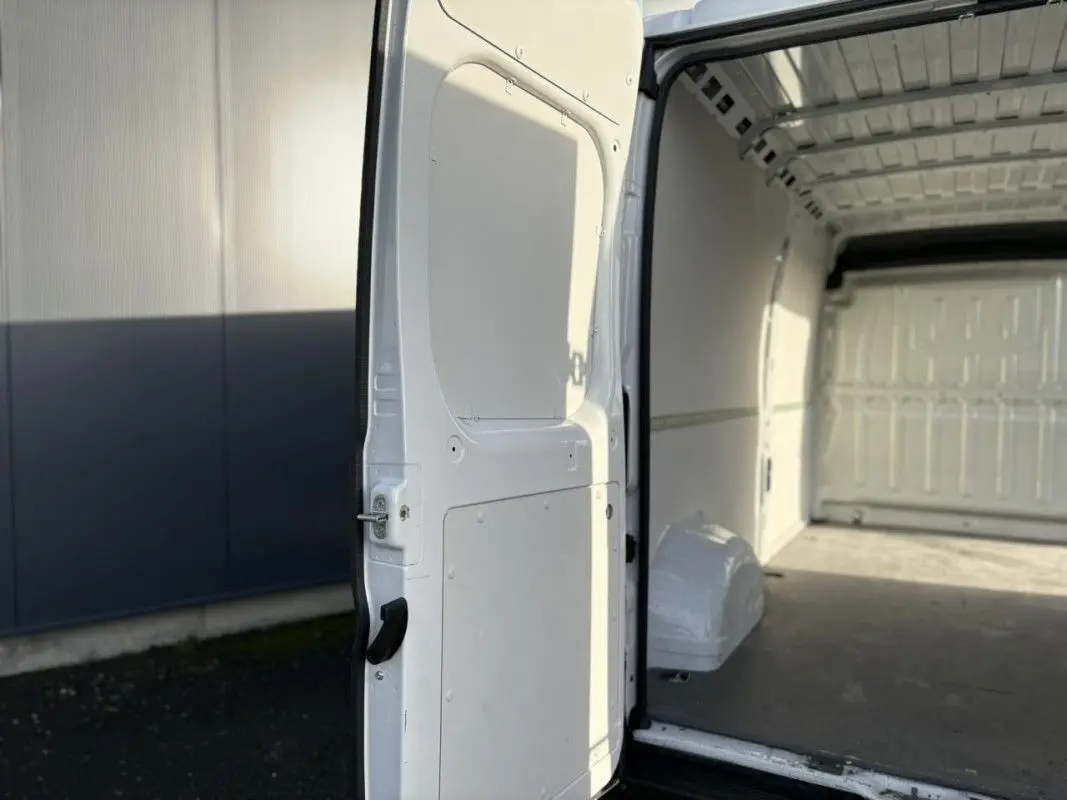 Vue intérieure côté droit du fourgon blanc Opel Movano 2.2 BlueHDi 140 L3H2 avec porte arrière ouverte et espace de chargement vide.